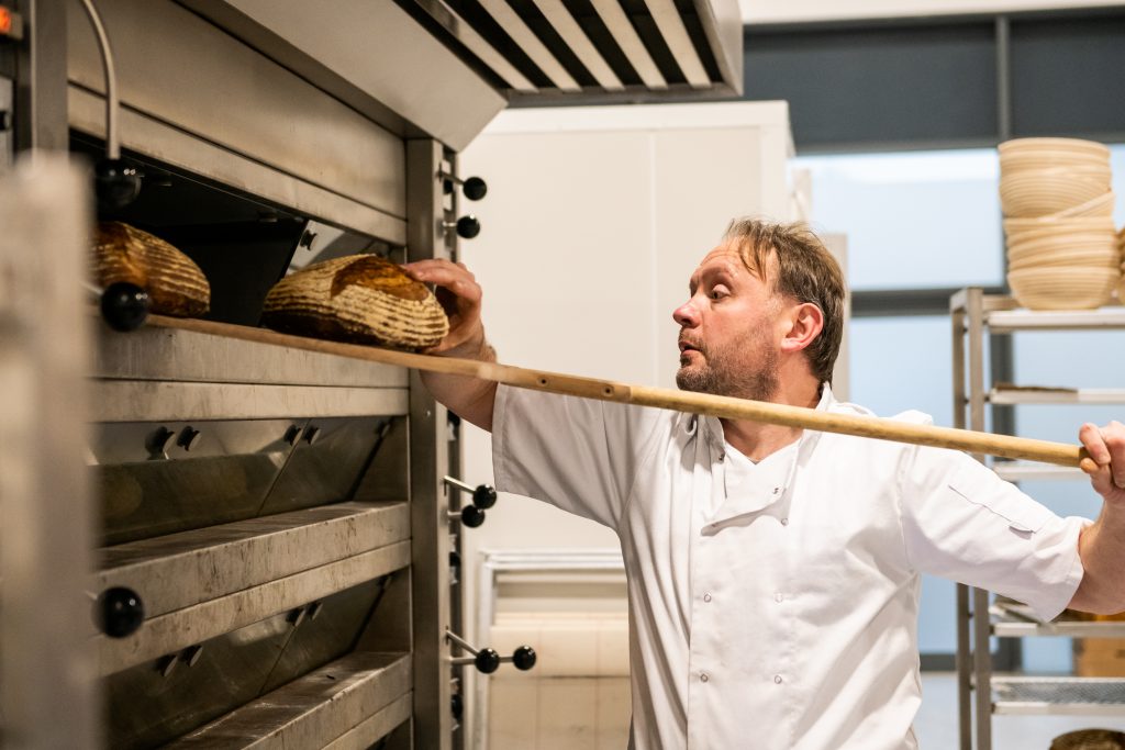 Baker taking bread from oven