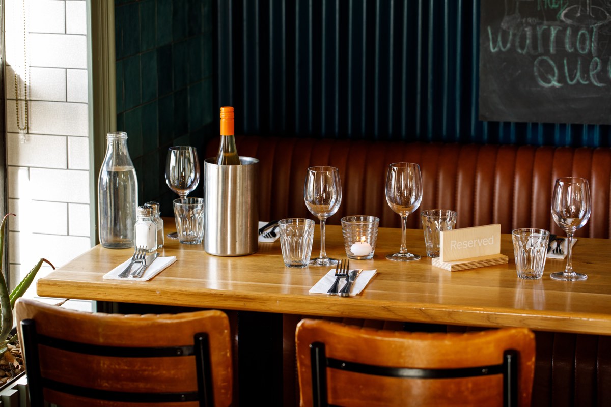 A reserved table set with glasses and a wine cooler at Honestly