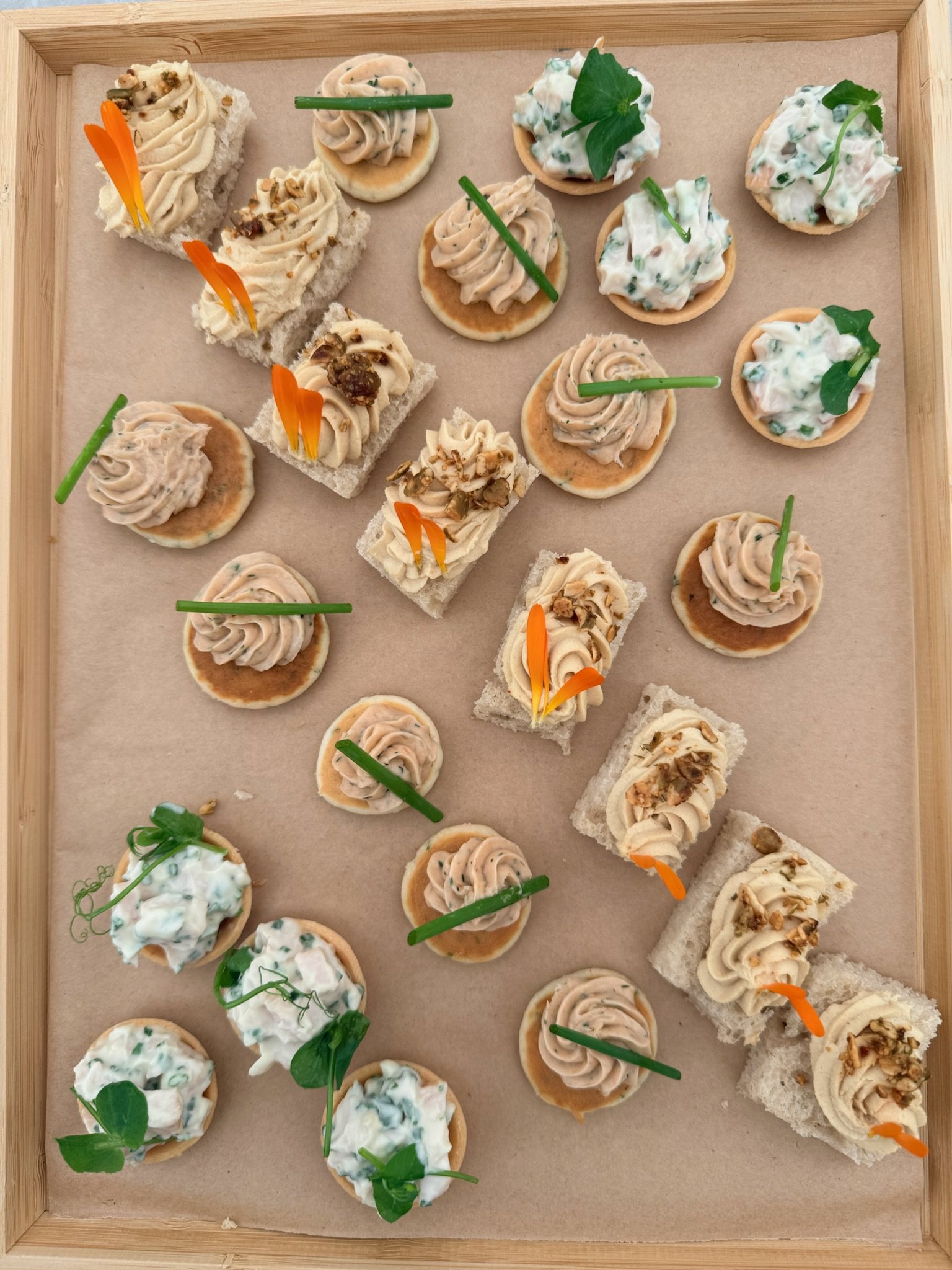 A tray of Honestly canapés: blinis with smoked salmon and tartlets with herb crème fraîche