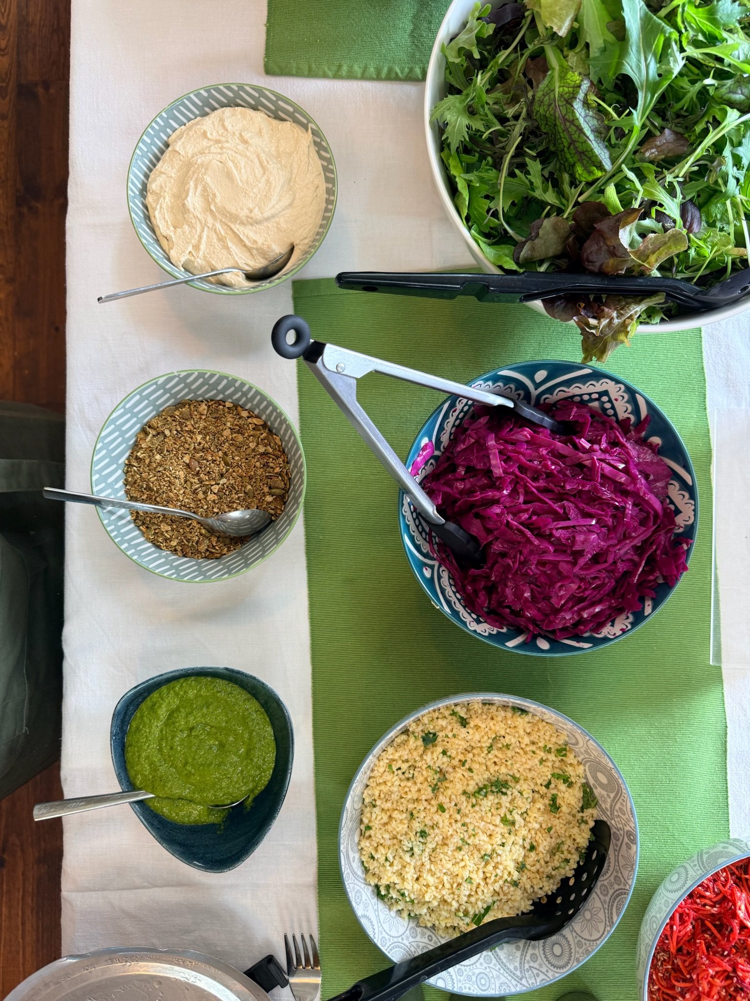 Honestly salads set out on the buffet: hummus, pickled red cabbage, bulgur and kale, dressed leaves and toasted seeds